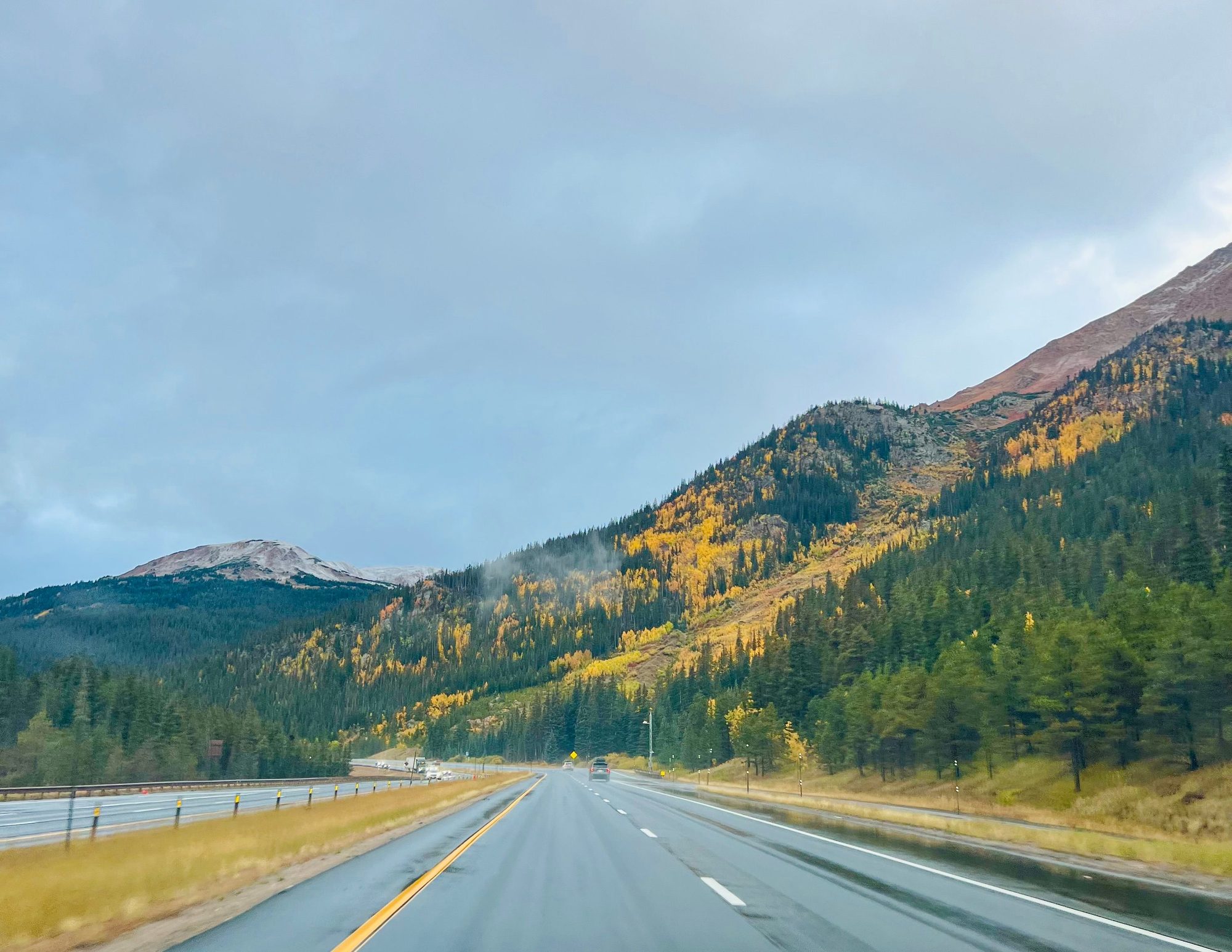 Driving a mountain pass past hillsides of yellow aspen in autumn